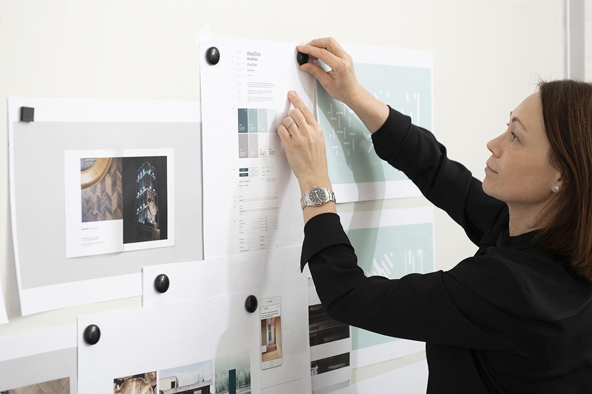 Billede af kreativ projektleder der hænger materiale op på væggen